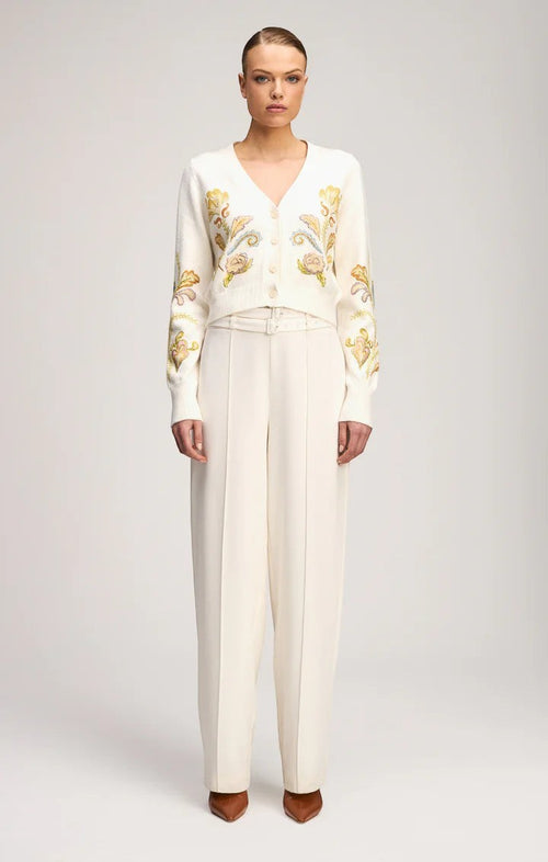 Coats and co. cream V-neck cardigan with floral embroidery, button-down front, and ribbed trim worn with cream trousers.